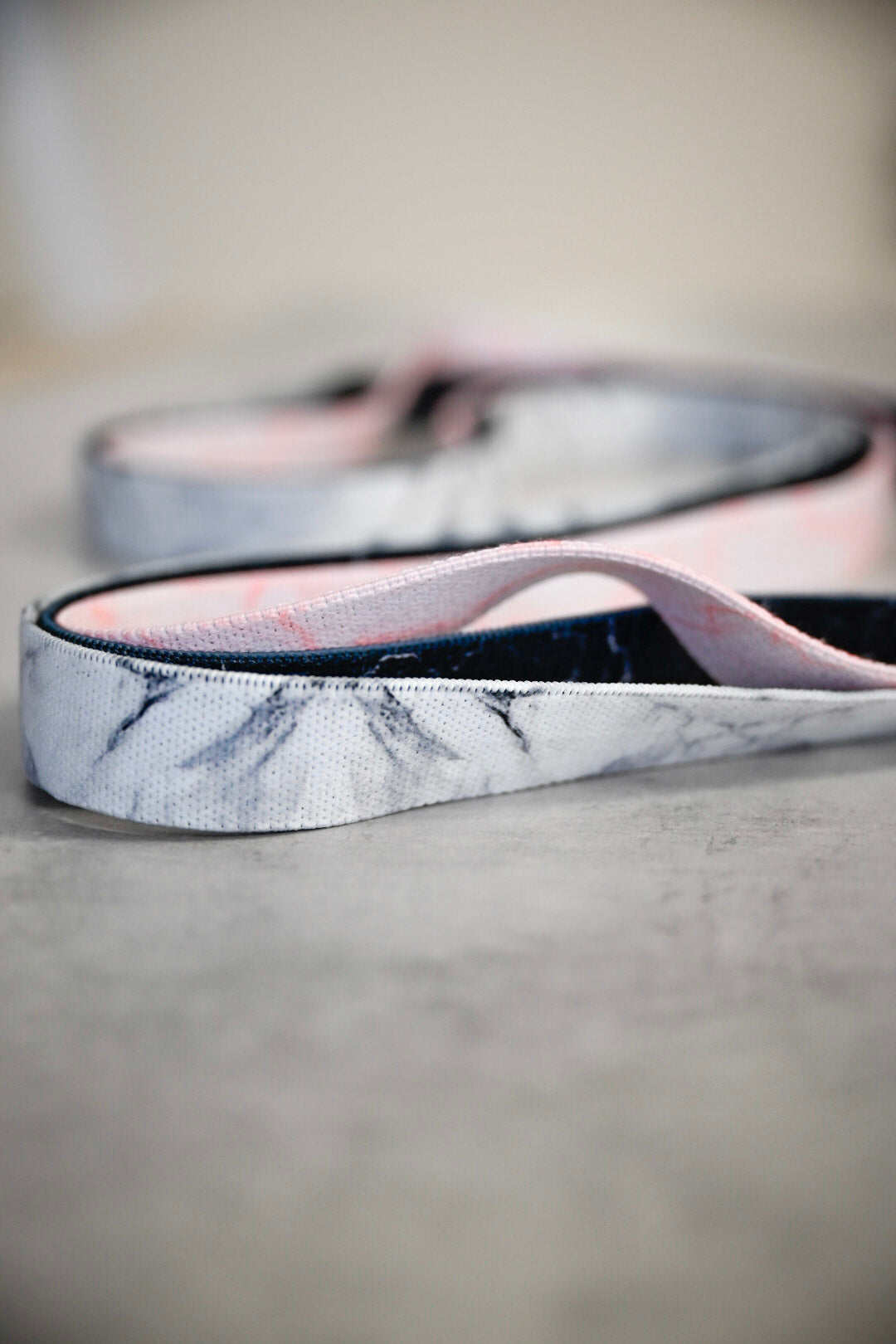 Three elastic fabric fitness bands in different colours; white, pale pink and black, with a marble pattern over each different colour.