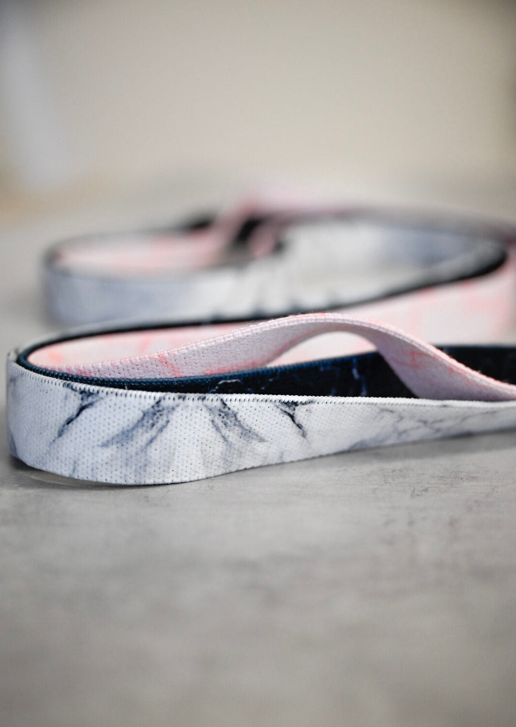 Three fabric elastic fitness bands, in white, pale pink and black with a marble pattern on each.